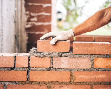 worker putting cement on brick stacked betwwen each other